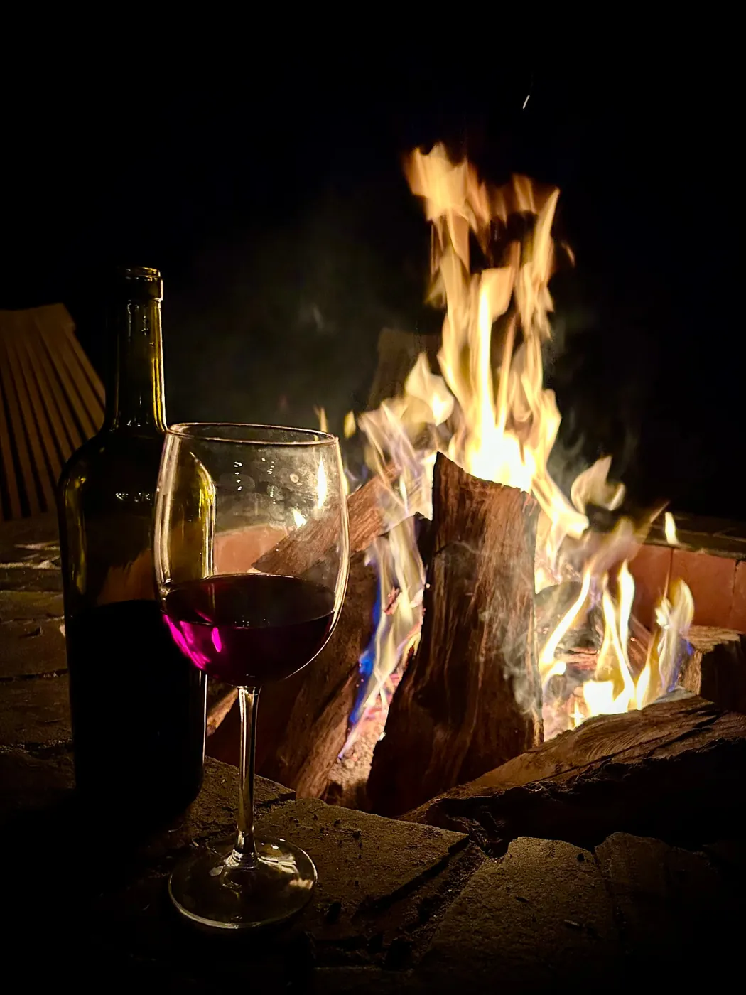 Copa de vino tinto junto a la fogata
